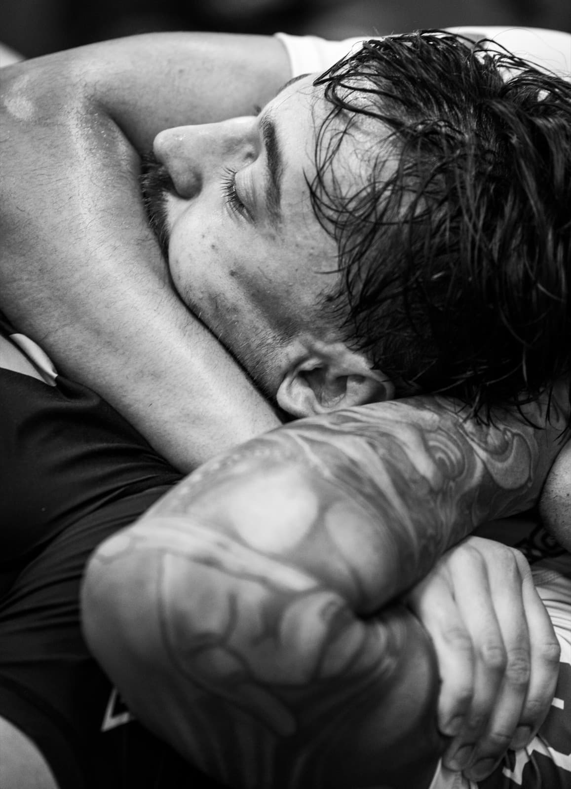 Editorial black and white BJJ photo, a choke being applied mid-roll